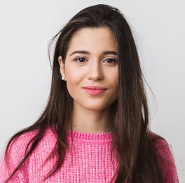 Woman with long dark hair wearing a pink knitted sweater