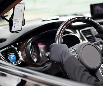 A cab with a driver on his board placed phone with a mobile application interface where shows a map and a route
