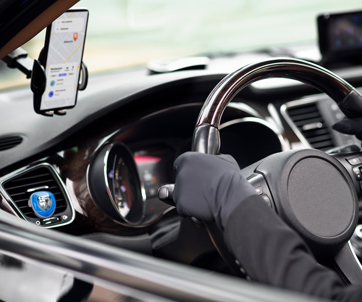 A cab with a driver on his board placed phone with a mobile application interface where shows a map and a route